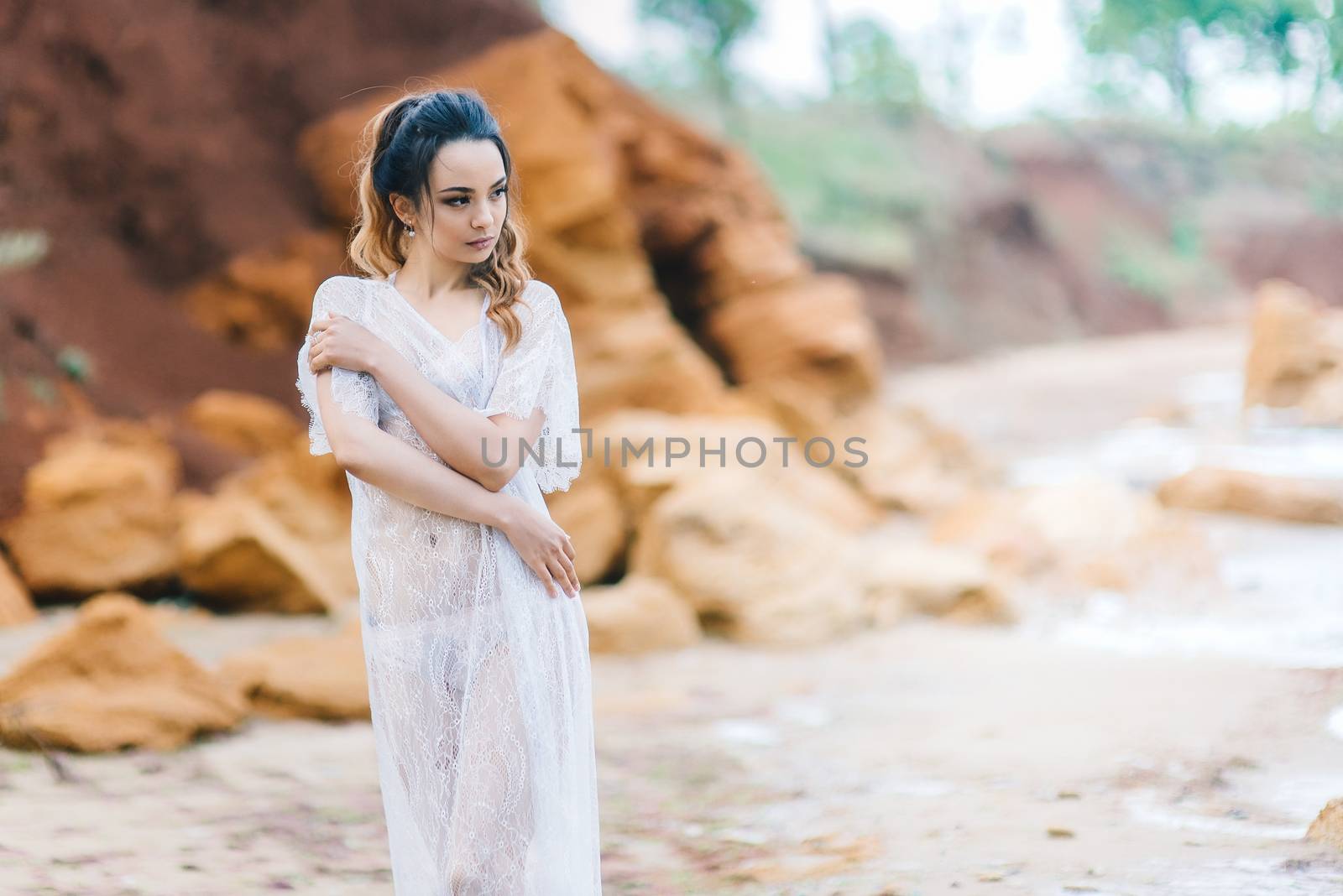 bride in her underwear and a dressing gown with a veil walks on the beach