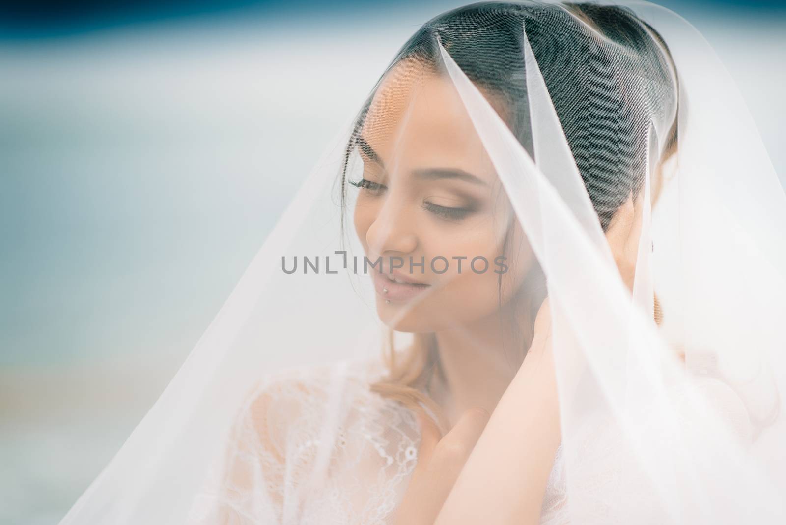 bride close-up under a veil against a background of blue sky and black sea