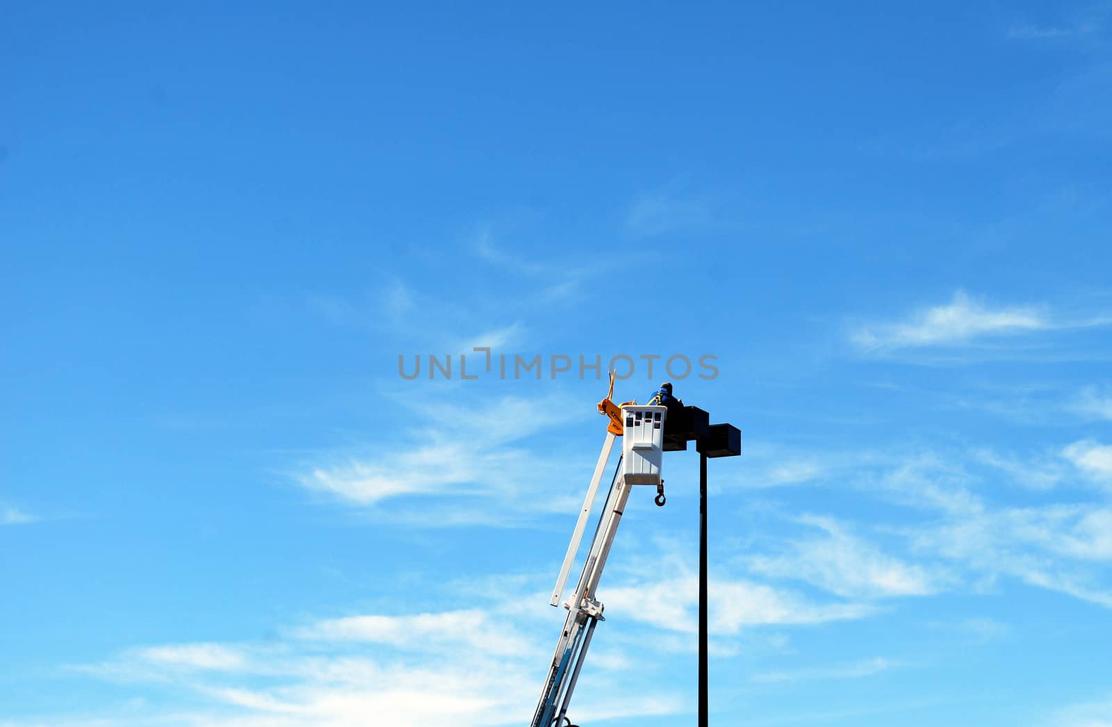 Utility worker replacing a broken lamp in a shopping mall outdoors.