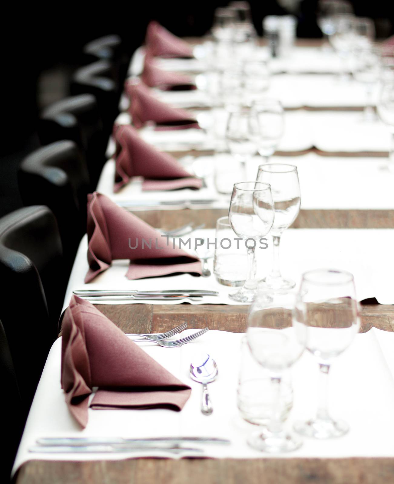 Restaurant Table Setting with Glasses, Silverware and Napkins on Vintage Wooden Table with Chairs closeup. Focus on Forks