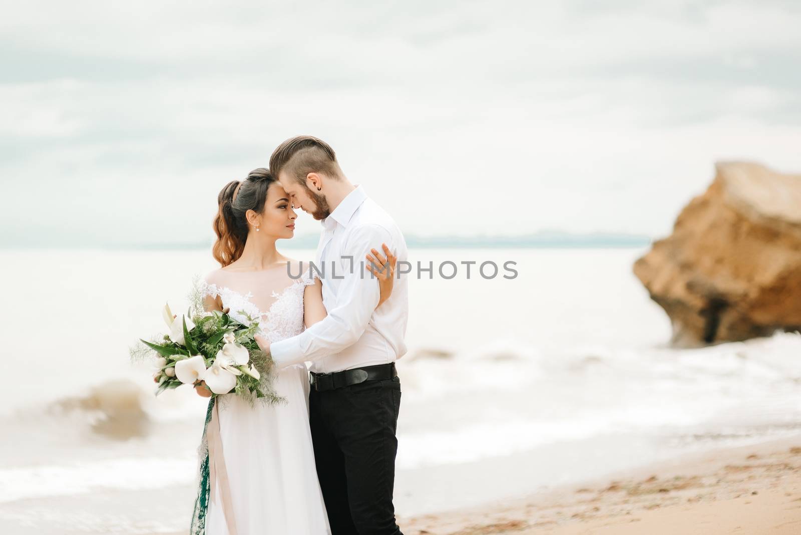 young couple groom with the bride on a sandy beach at a wedding walk