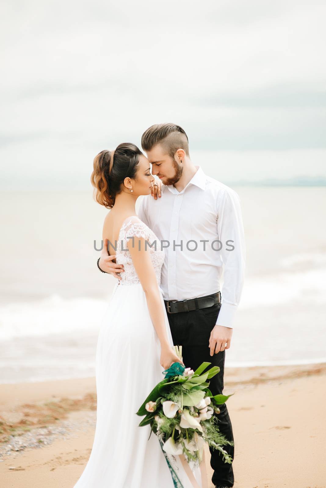 young couple groom with the bride on a sandy beach at a wedding walk