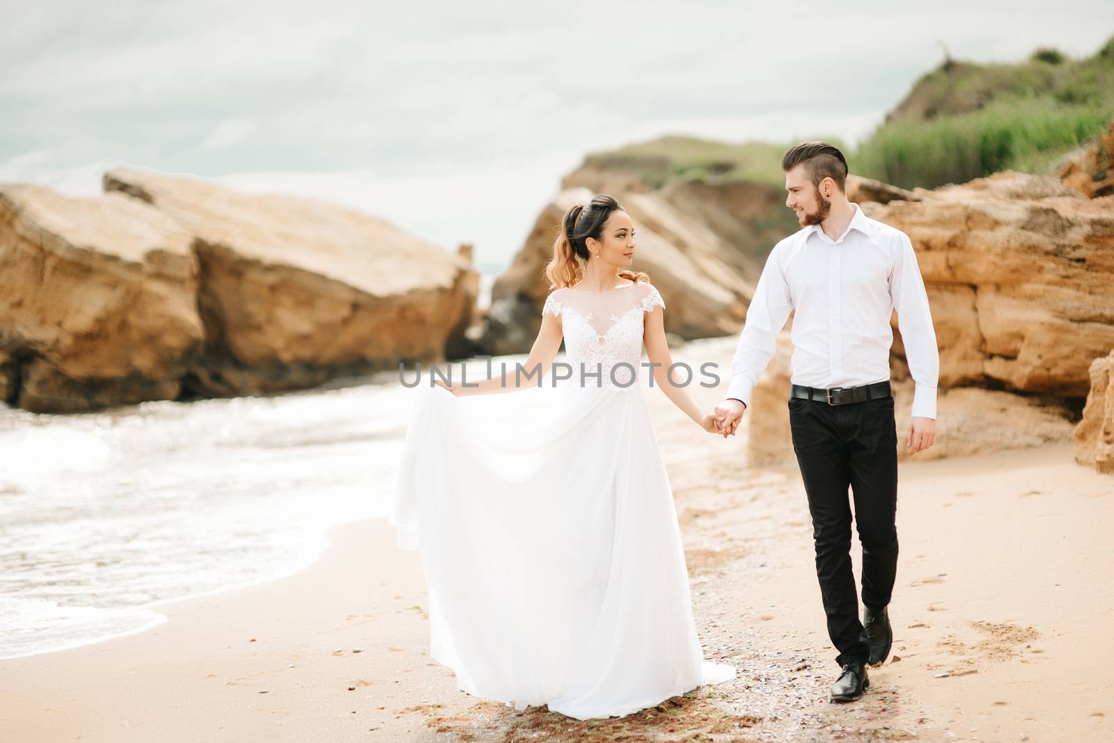 young couple groom with the bride on a sandy beach at a wedding walk