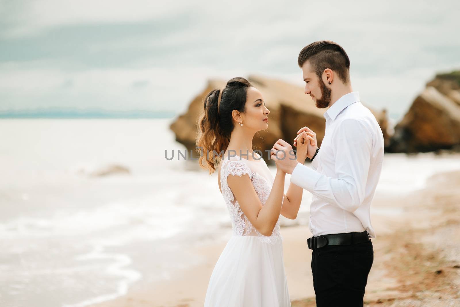 young couple groom with the bride on a sandy beach at a wedding walk