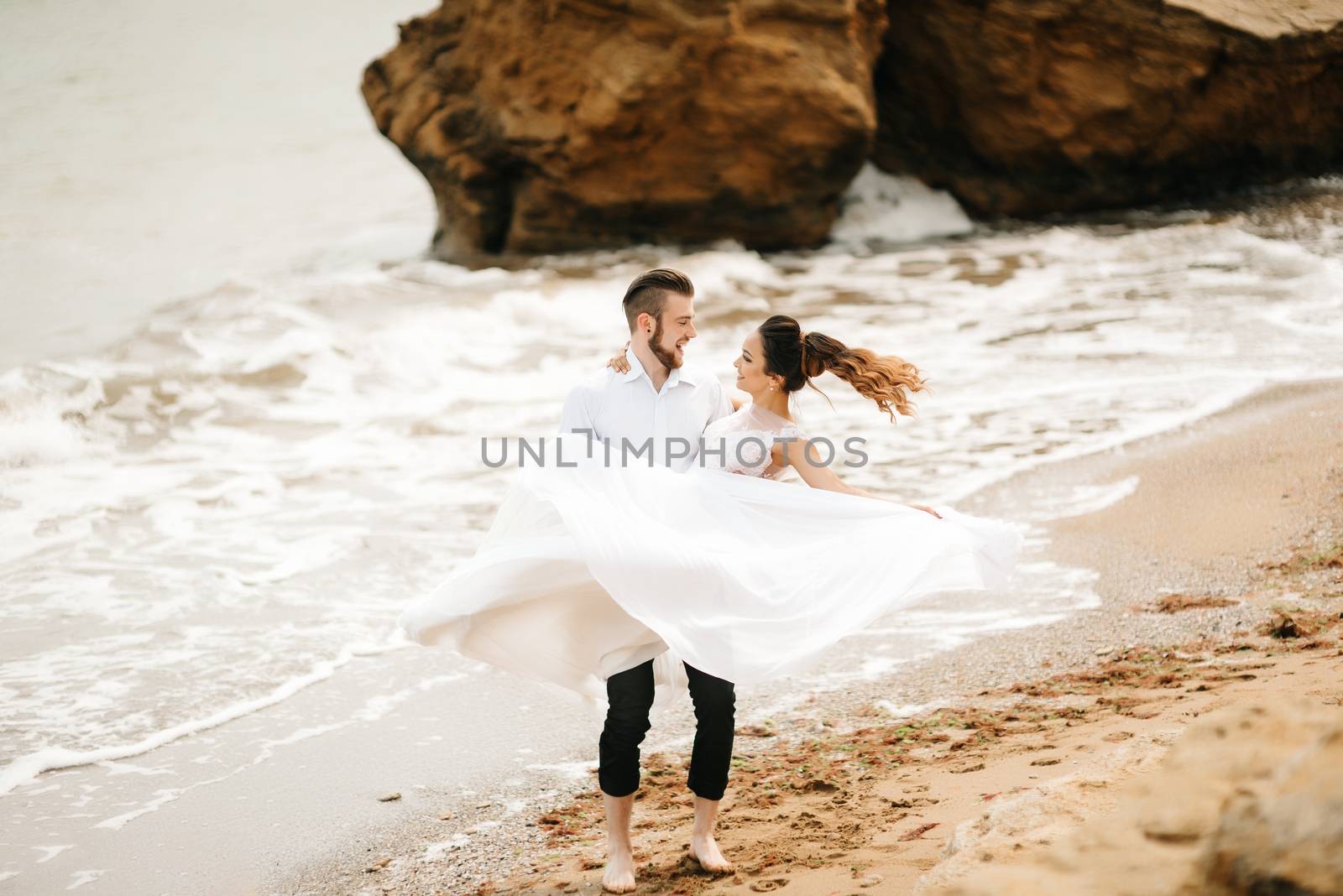 young couple groom with the bride on a sandy beach at a wedding walk