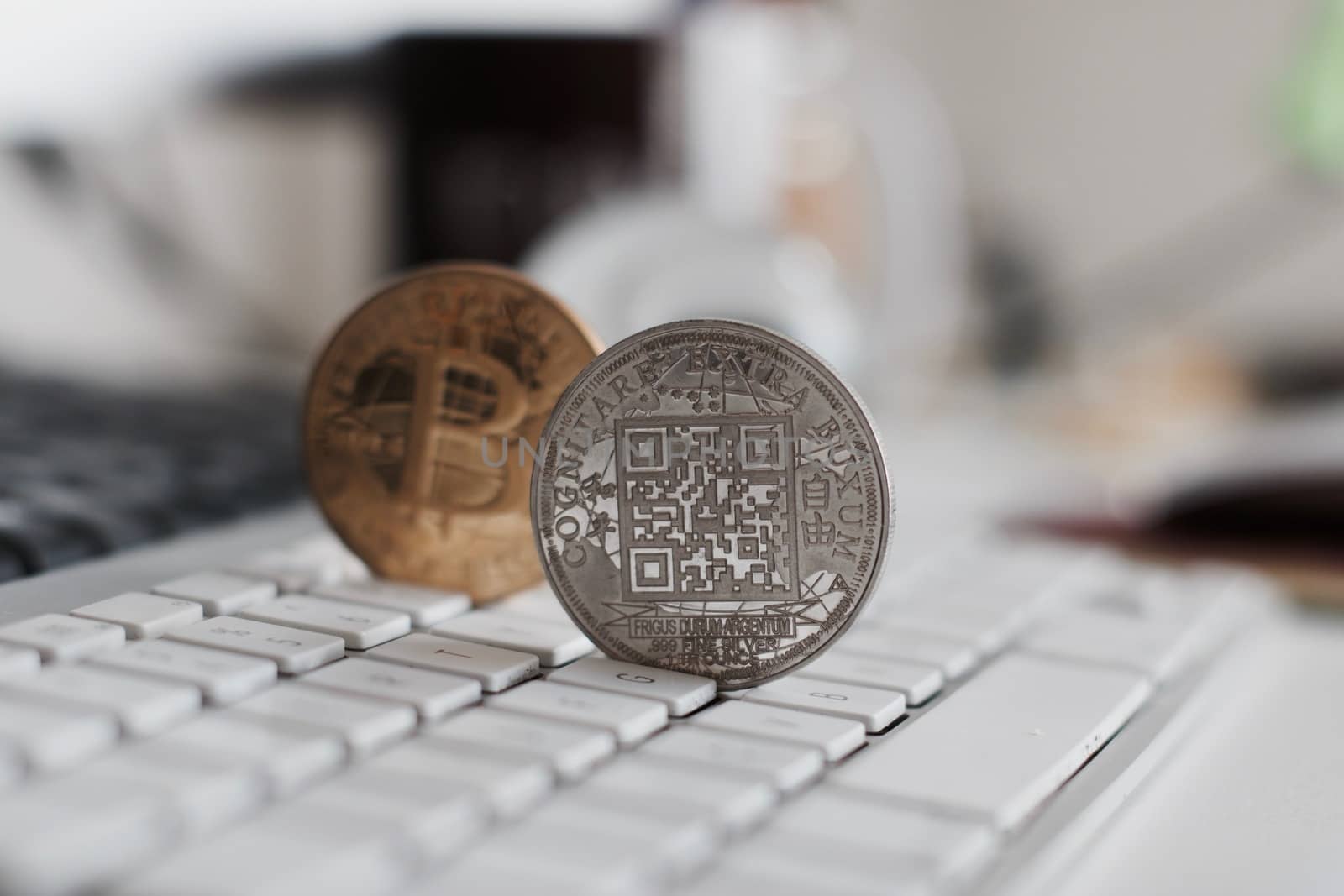Digital currency physical metal bitcoin coin on the white keyboard near glass ball.