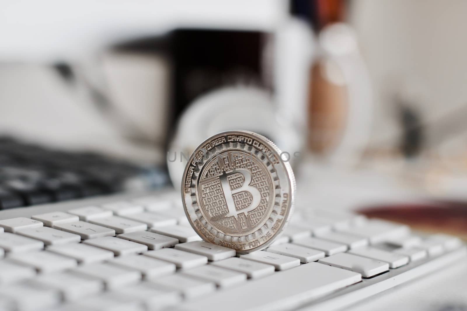 Digital currency physical metal bitcoin coin on the white keyboard near glass ball.
