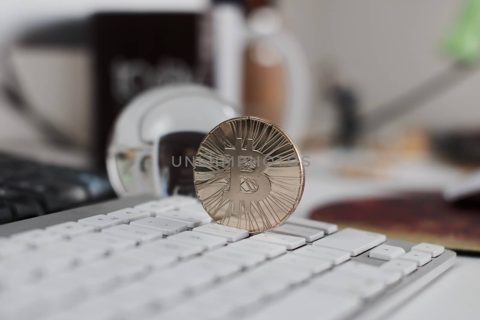 Digital currency physical metal bitcoin coin on the white keyboard near glass ball.