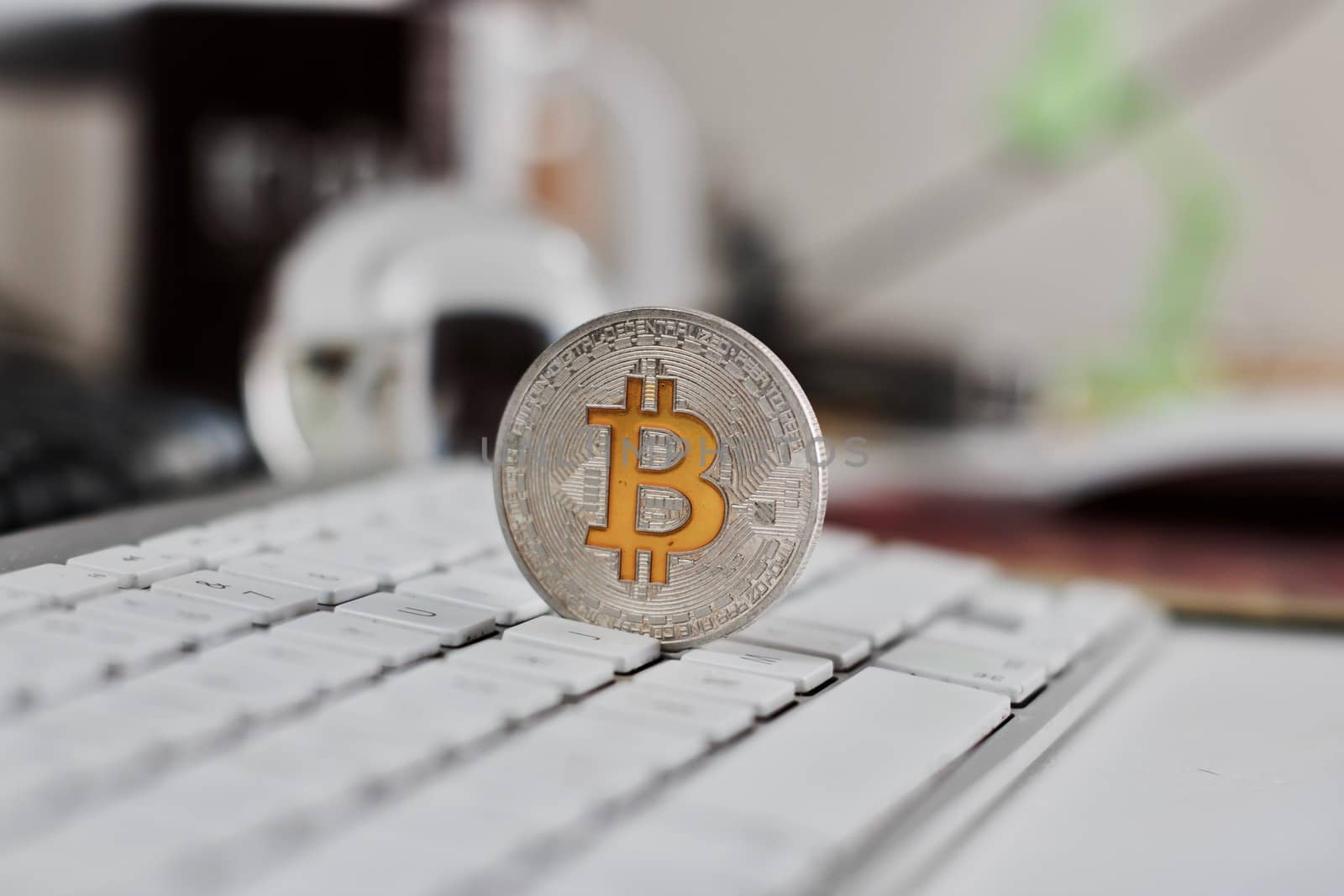 Digital currency physical metal bitcoin coin on the white keyboard near glass ball.