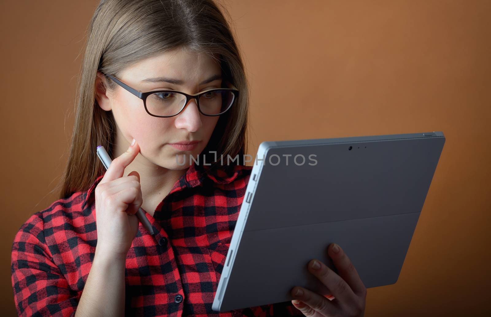 young teenage girl thinking with a tablet