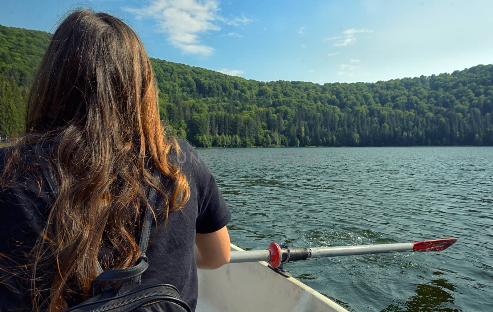 Teen girl back view sailing on lake