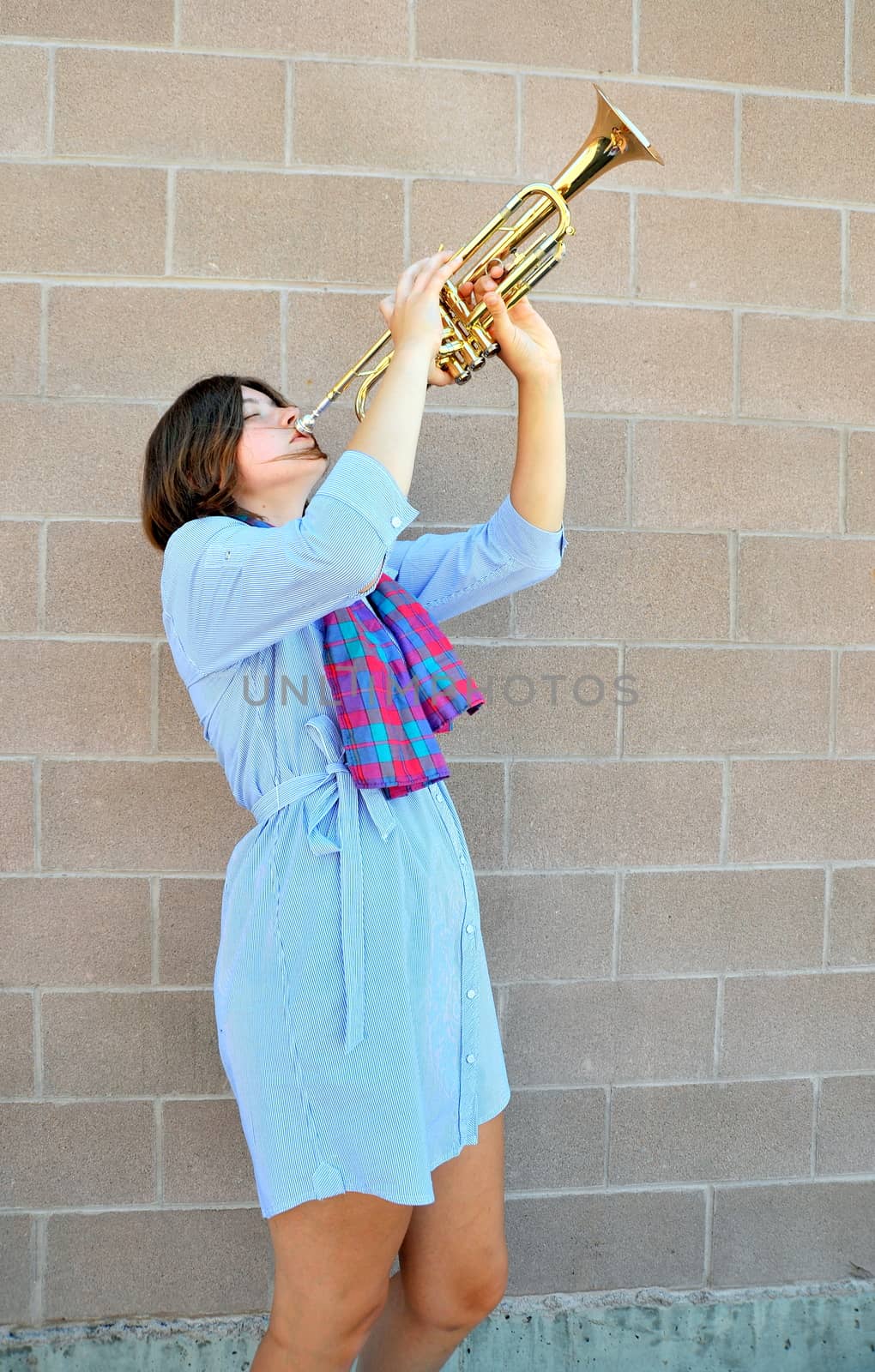 Female jazz trumpet player blowing her horn outside.