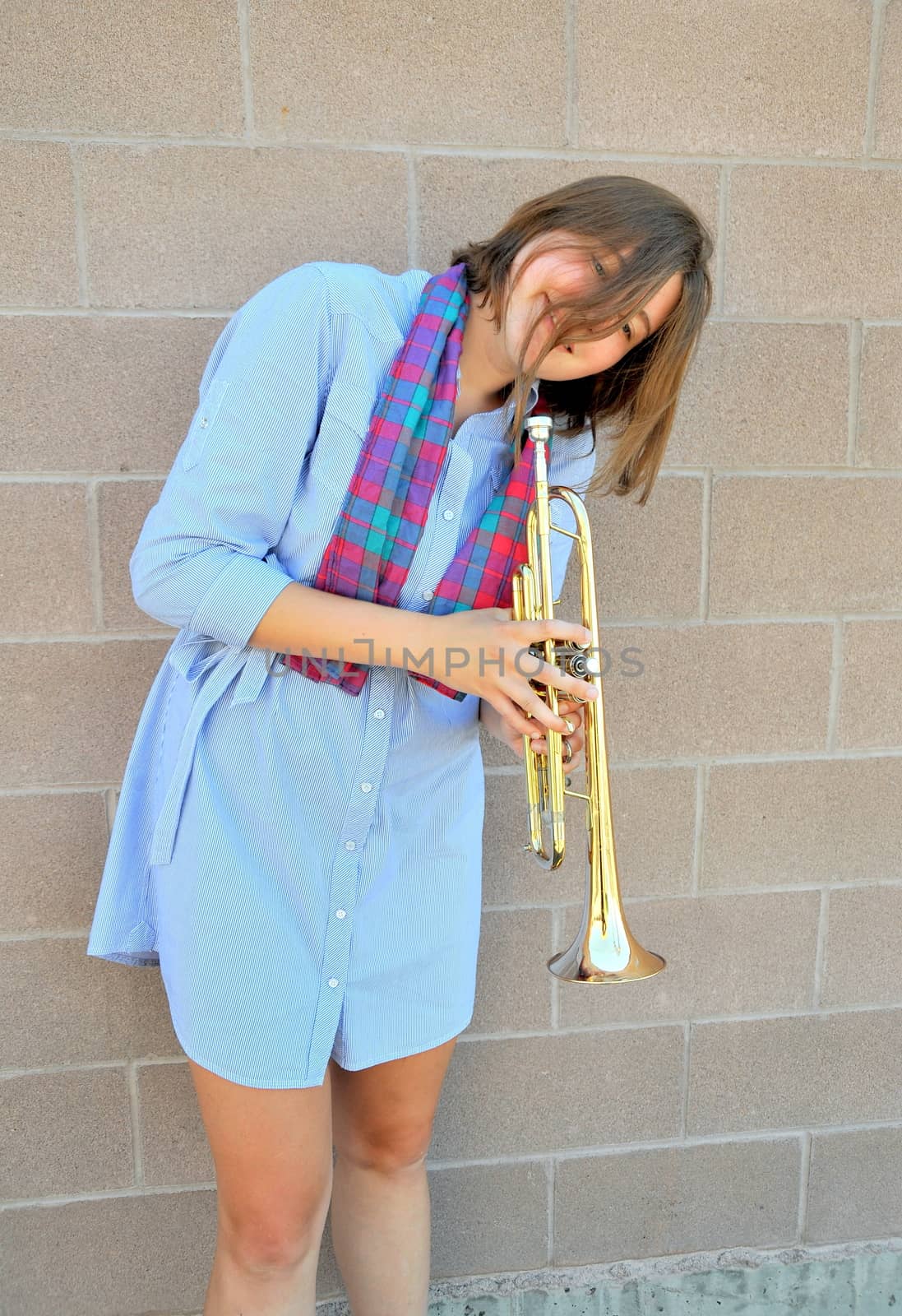 Female jazz trumpet player blowing her horn outside.