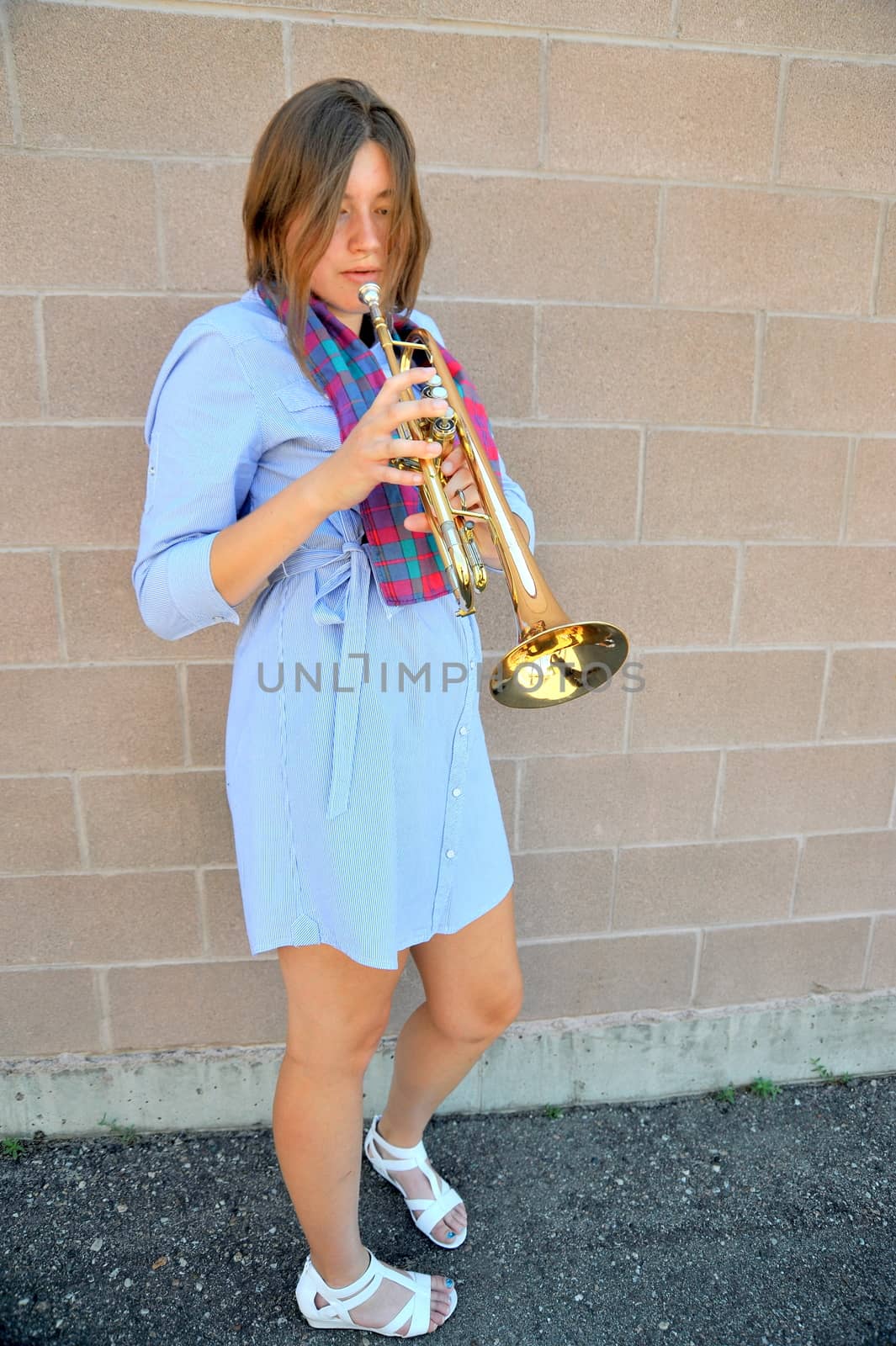 Female jazz trumpet player blowing her horn outside.