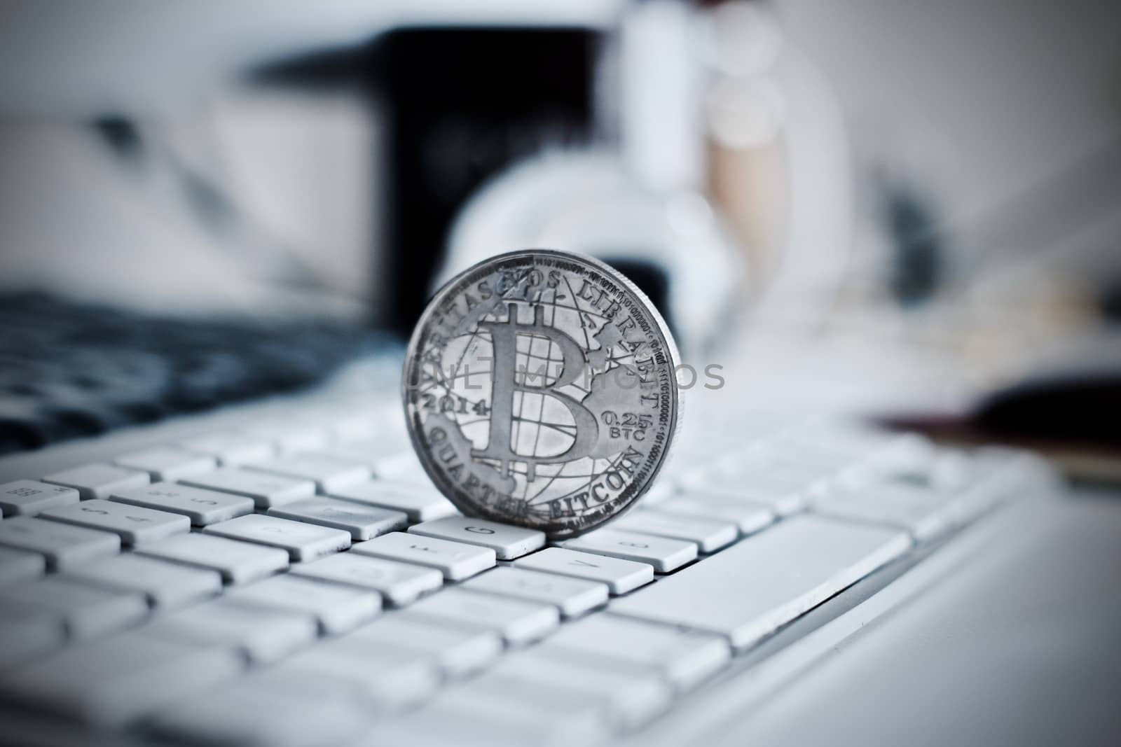 Digital currency physical metal bitcoin coin on the white keyboard near glass ball.