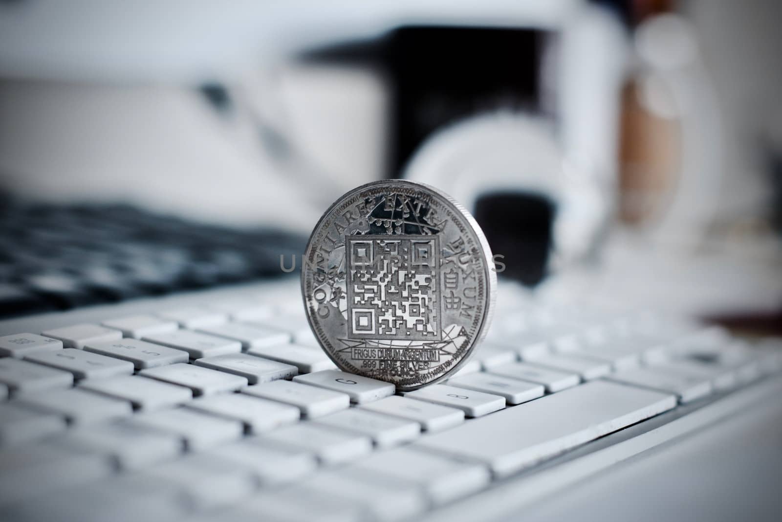 Digital currency physical metal bitcoin coin on the white keyboard near glass ball.