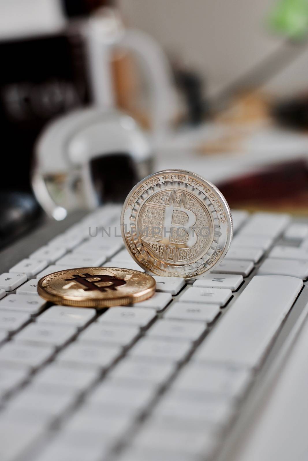 Digital currency physical metal bitcoin coin on the white keyboard near glass ball.
