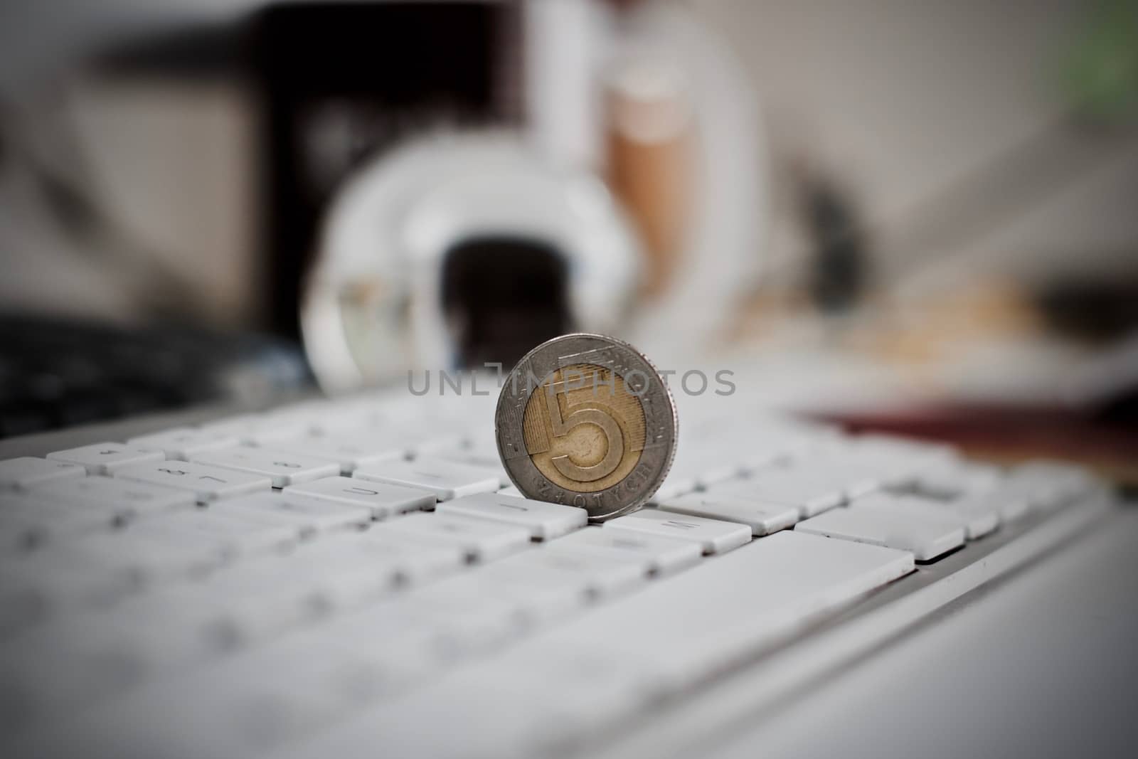 Physical coin polish money on the white computer keyboard.