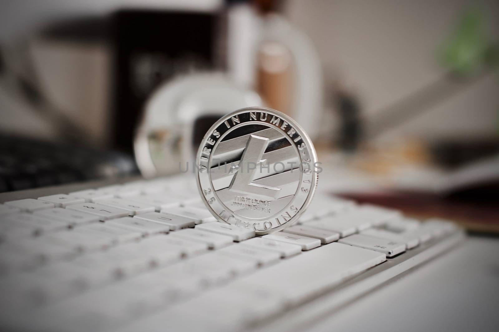 Digital currency physical litecoin coin on the white keyboard. Computer concept.