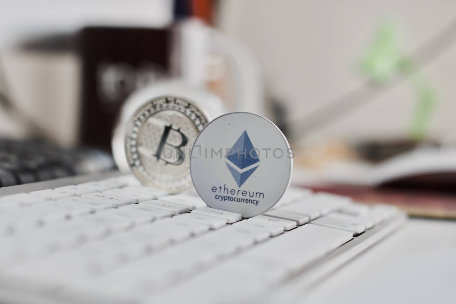 Digital currency physical metal bitcoin coin on the white keyboard near glass ball.