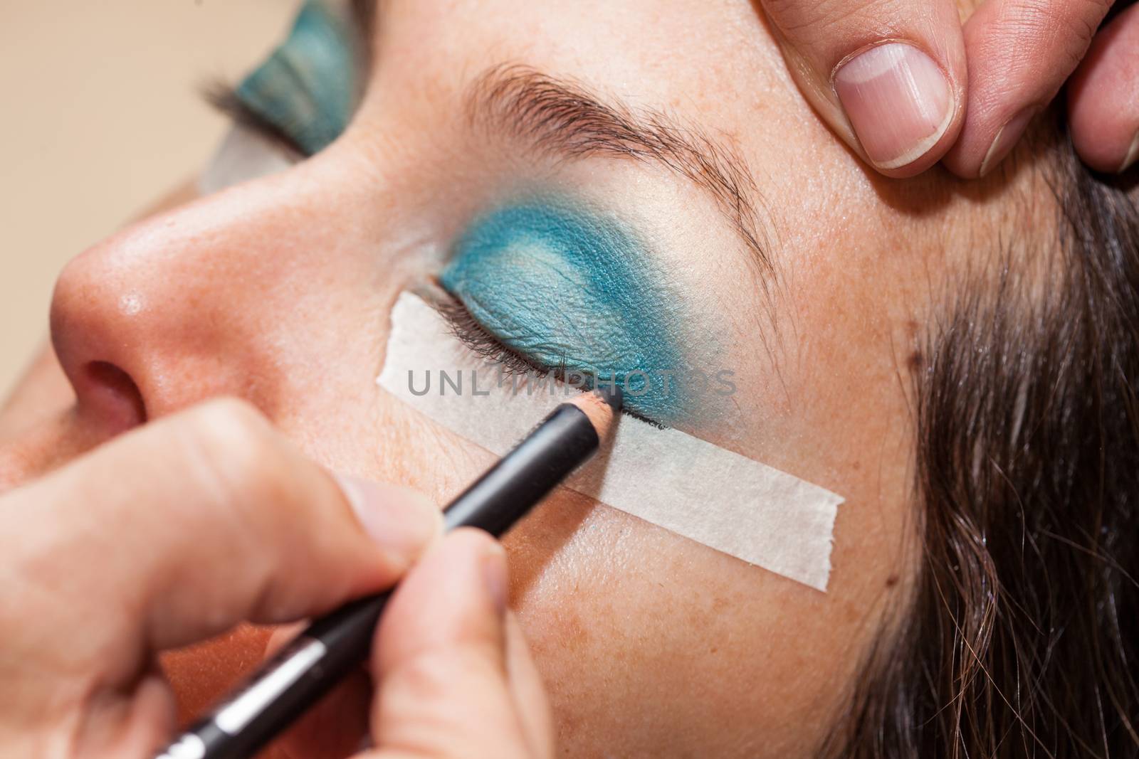 Make up artist using masking tape to create cat eyes