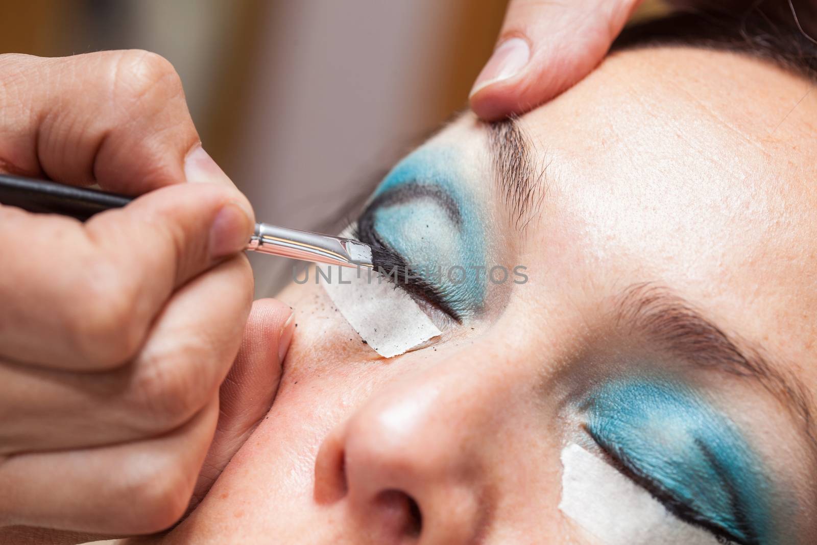 Make up artist creating cat eyes on a white woman