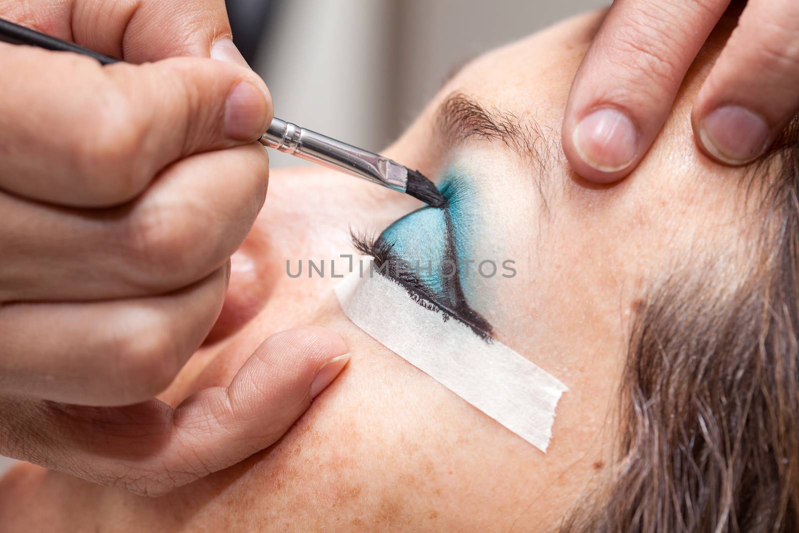 Make up artist creating cat eyes on a white woman