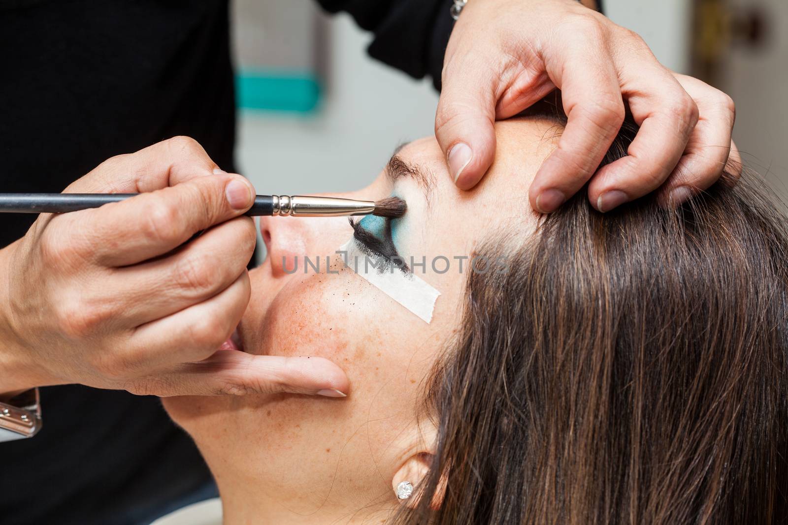 Make up artist creating cat eyes on a white woman