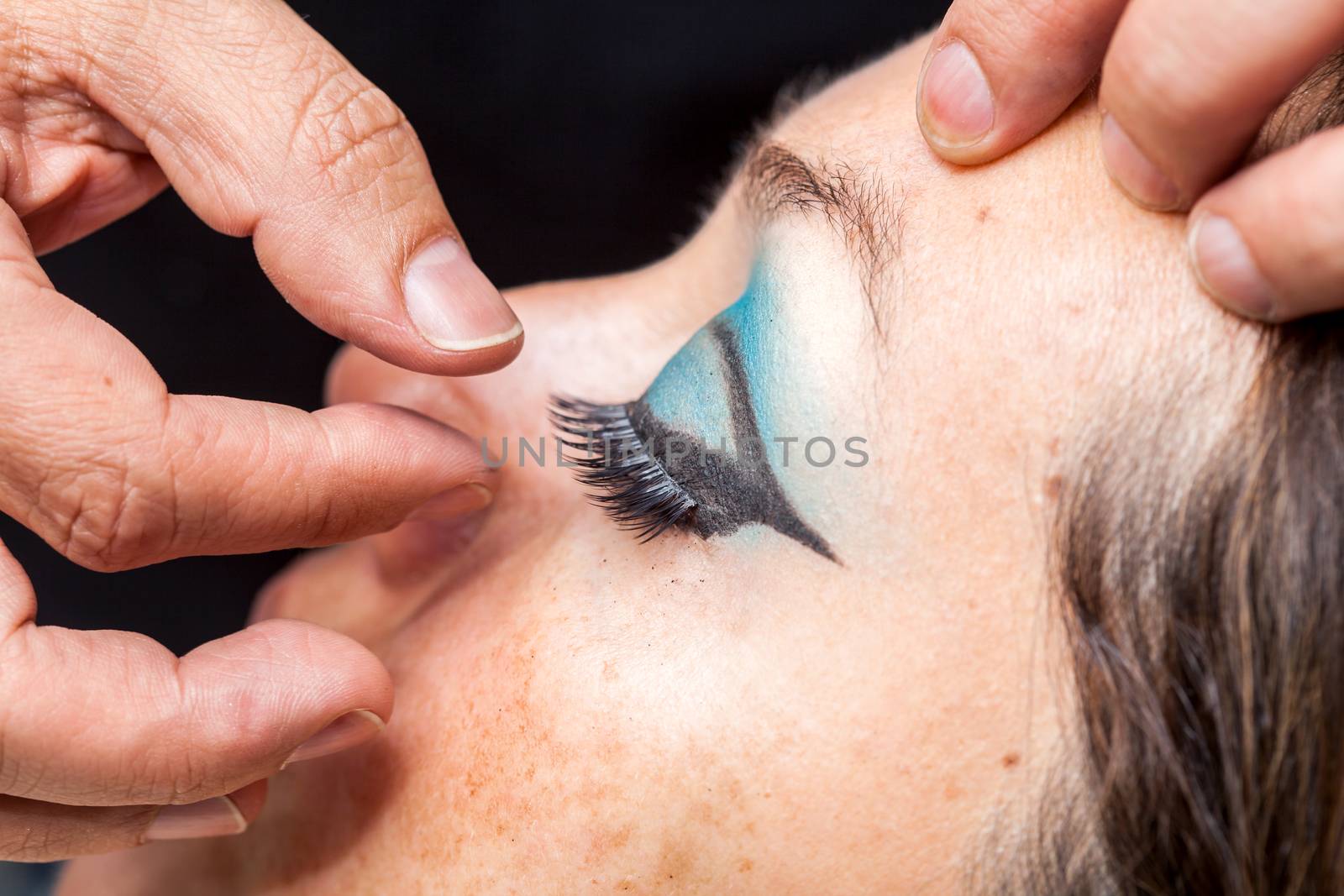 Close up of a makeup artist applying the false eyelashes to a woman