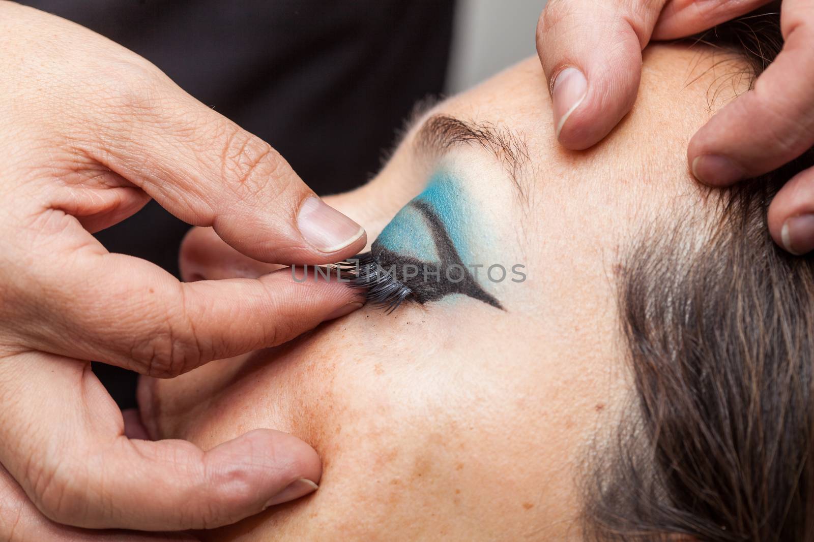 Close up of a makeup artist applying the false eyelashes to a woman