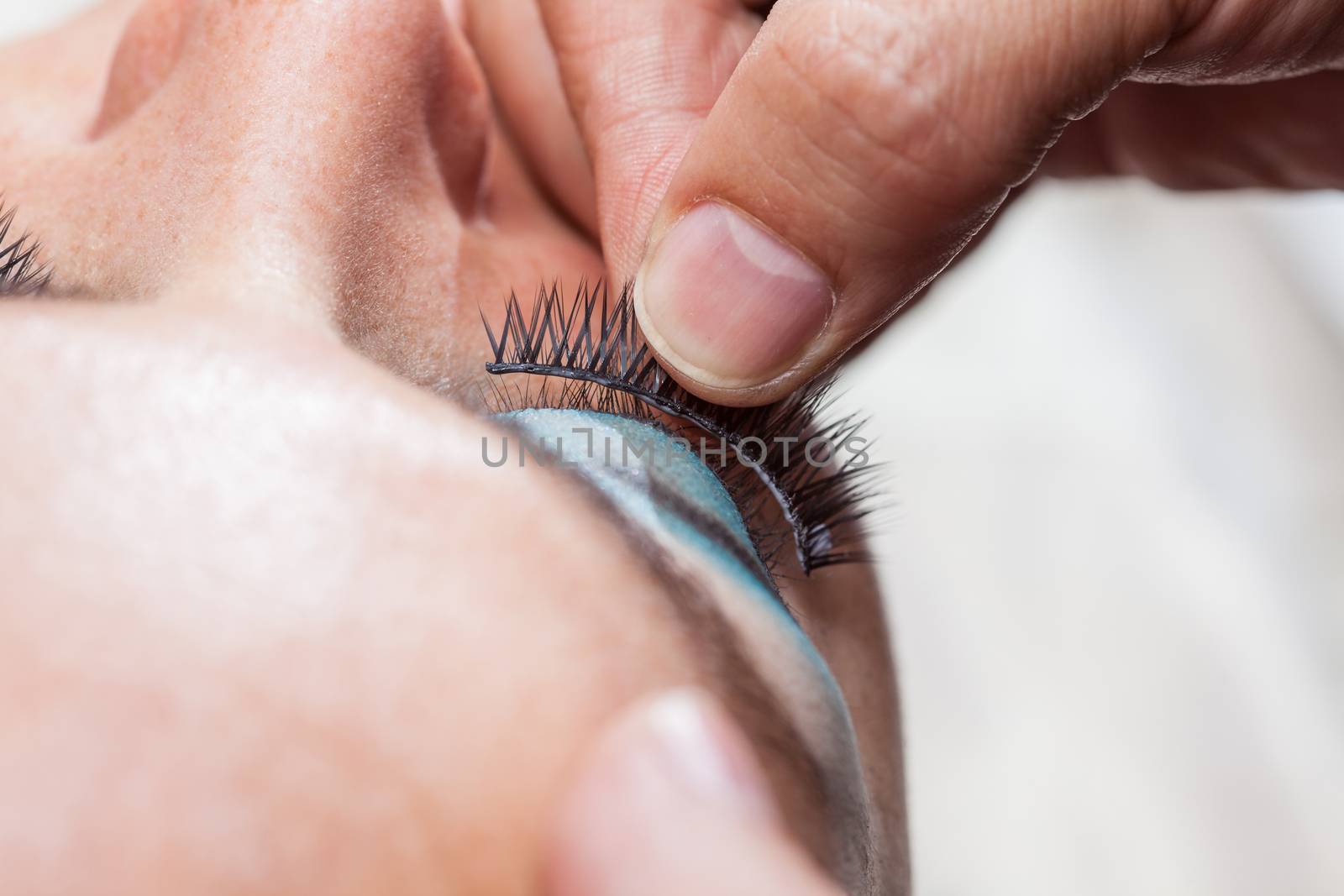 Close up of a makeup artist applying the false eyelashes to a woman