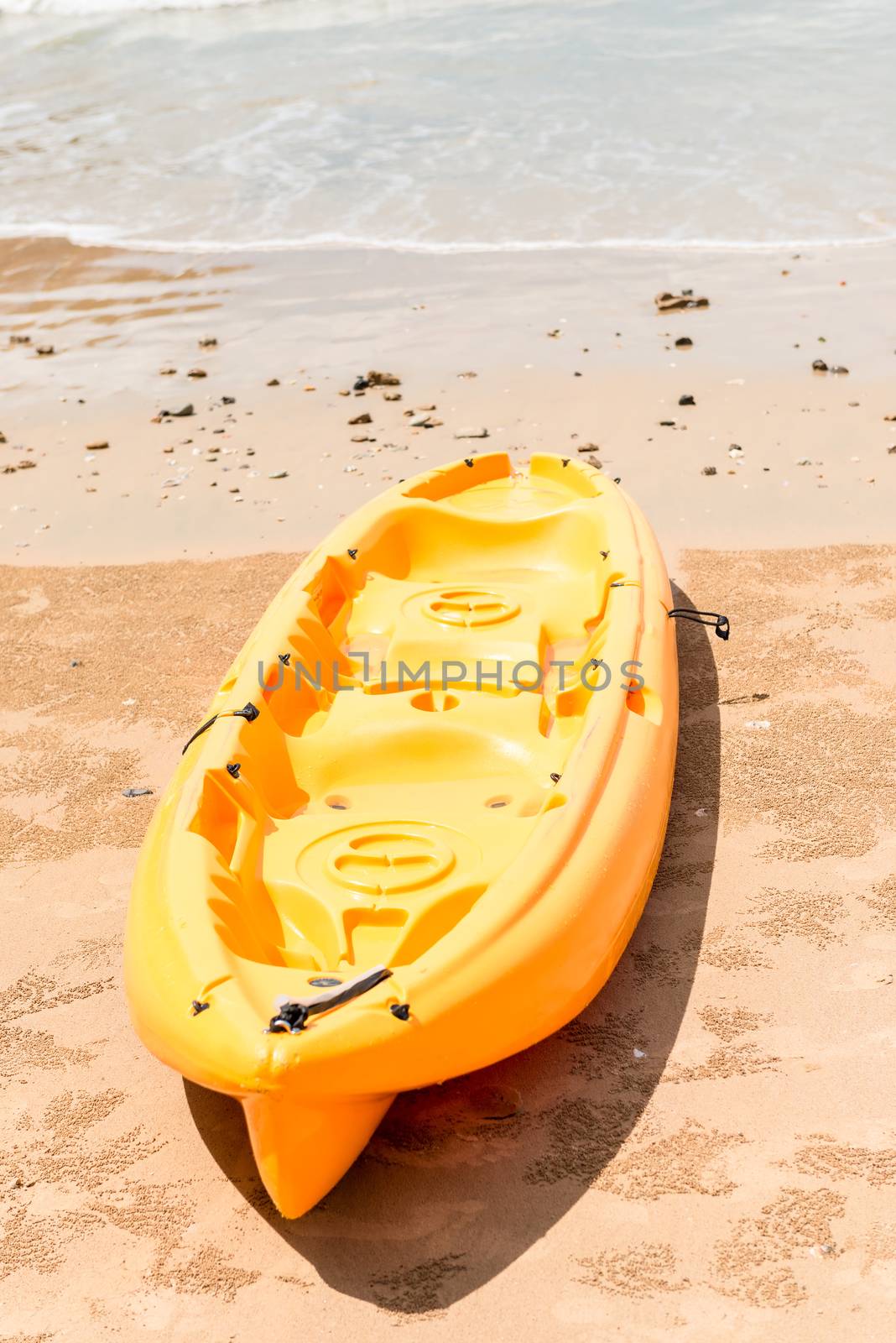 yellow plastic kayak lies on a sandy beach near the sea