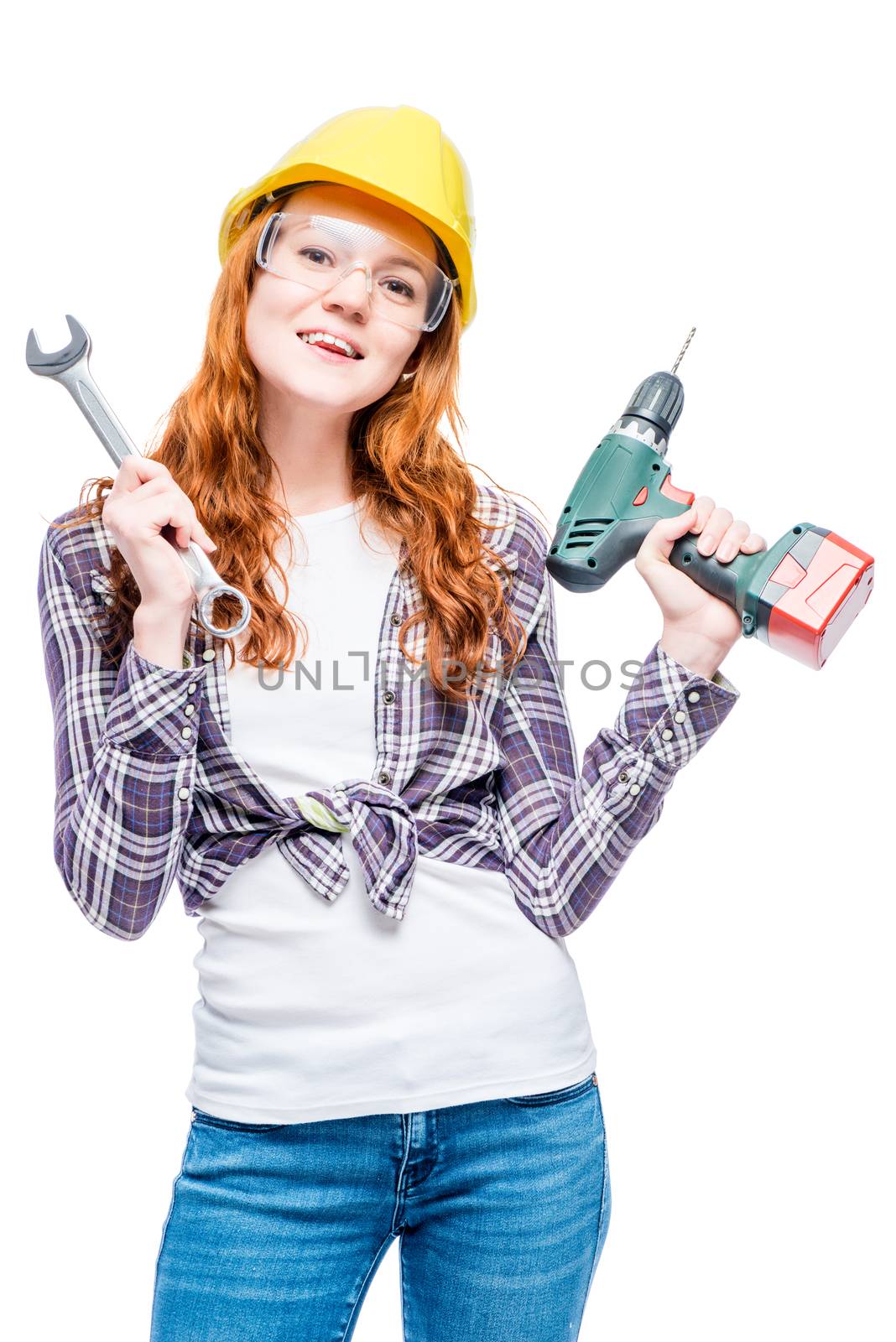 vertical portrait of a woman with red hair with tools in a yellow helmet isolated