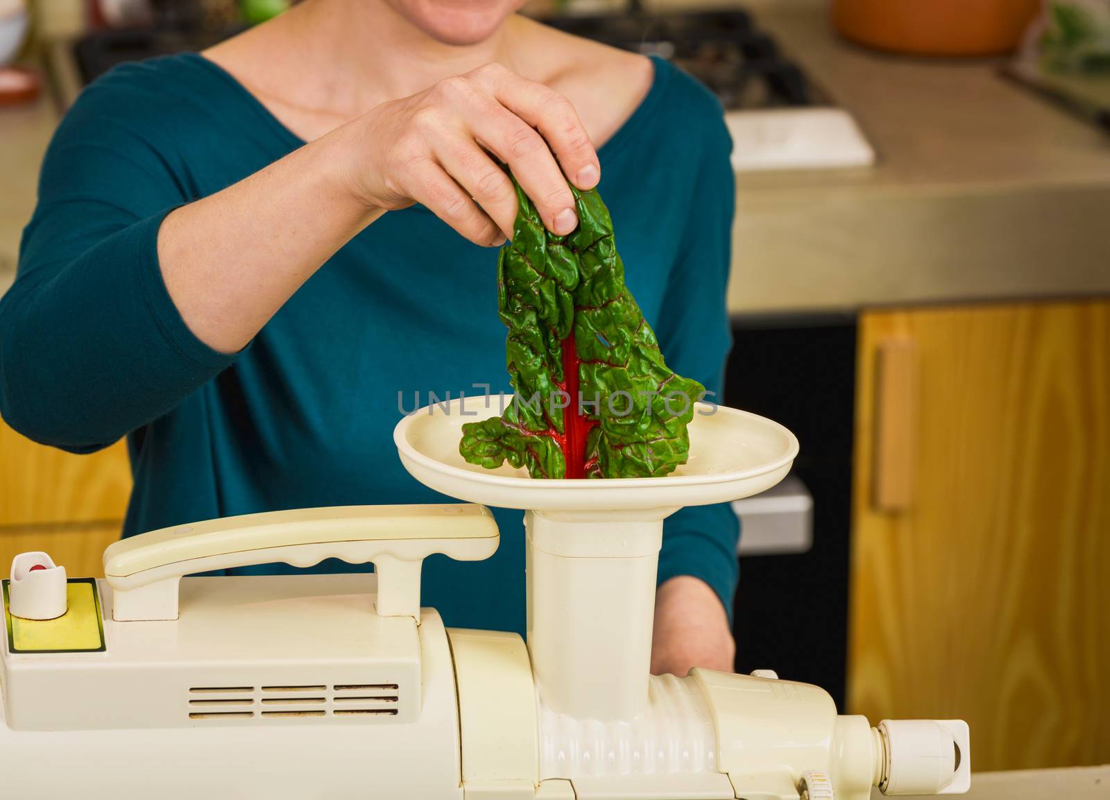 Woman using a centrifuge machine to prepare a detox juice. 