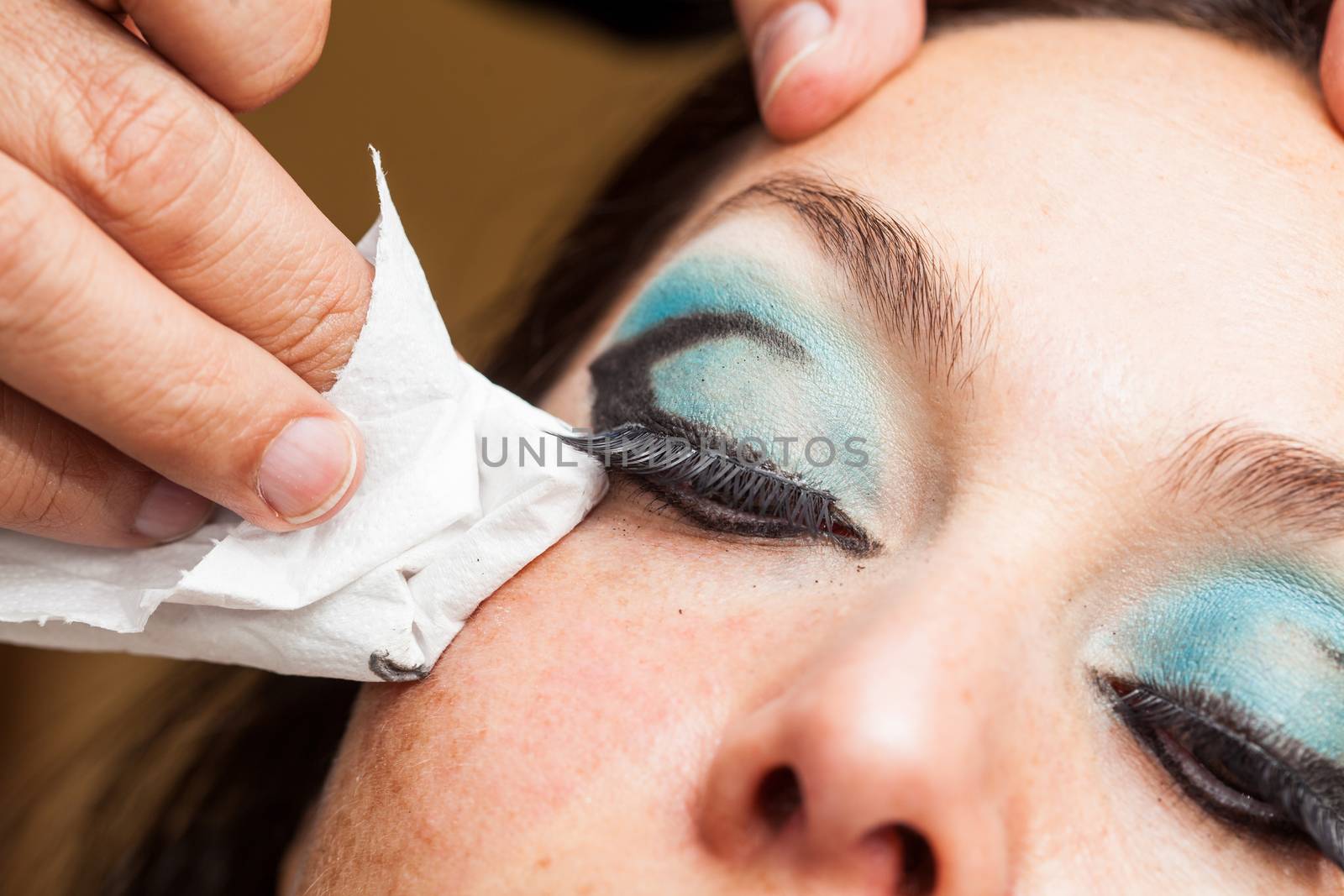 Makeup artist cleaning and giving the final touches to cat eyes makeup