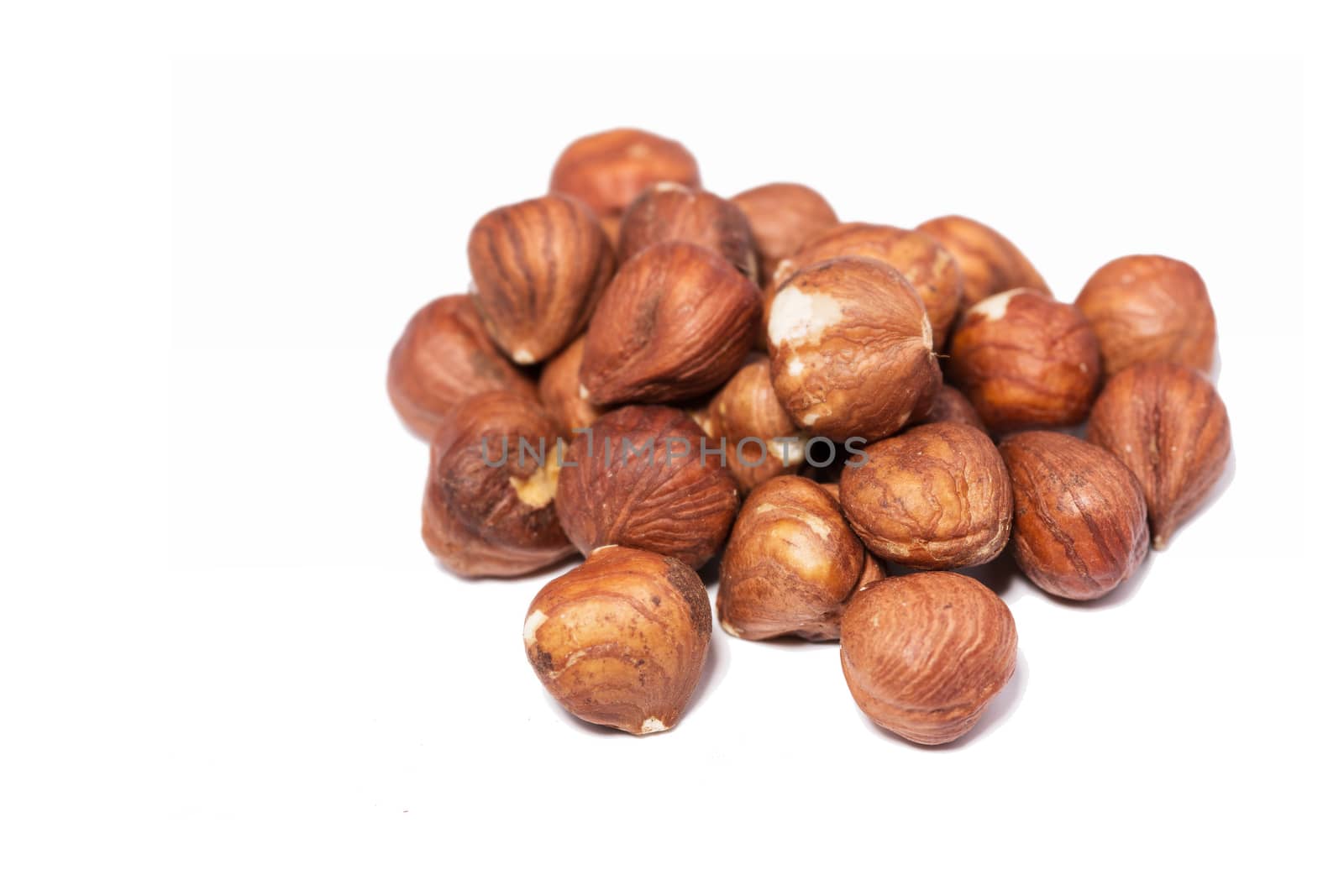 Many brown hazelnuts on white background