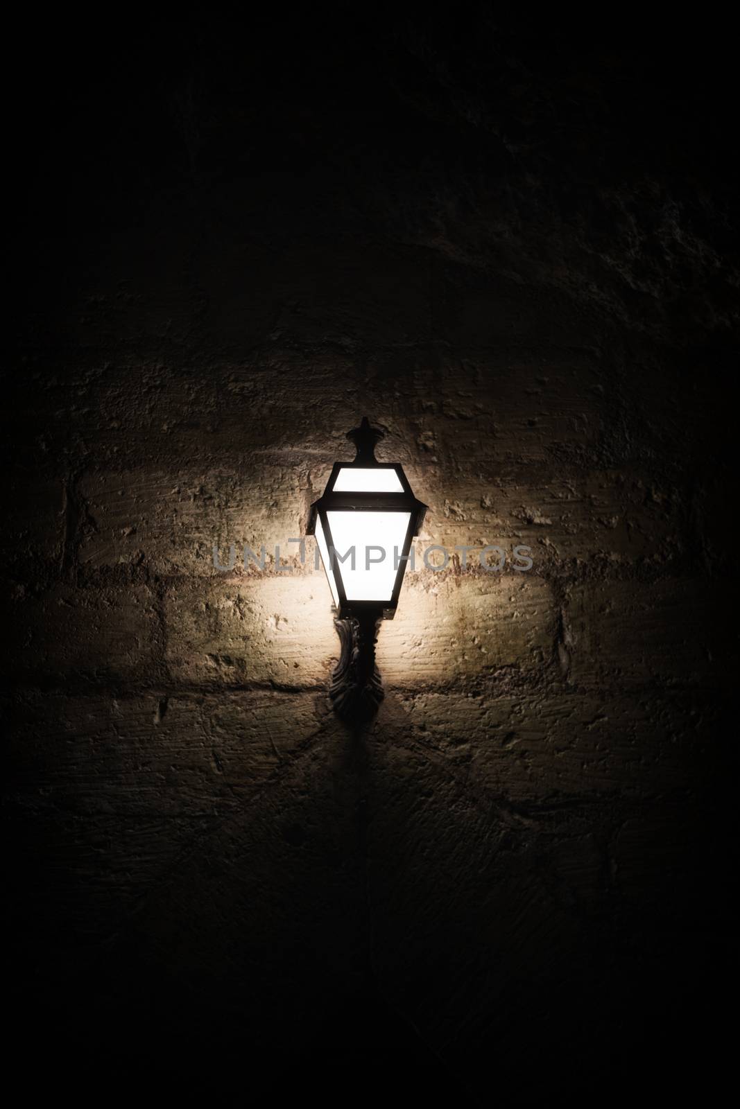 A luminous lantern on a stone wall by sandra_fotodesign