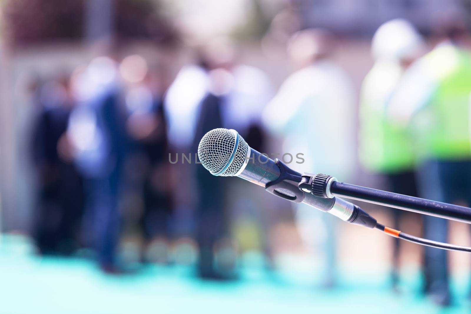 Microphone in focus against blurred group of people by wellphoto