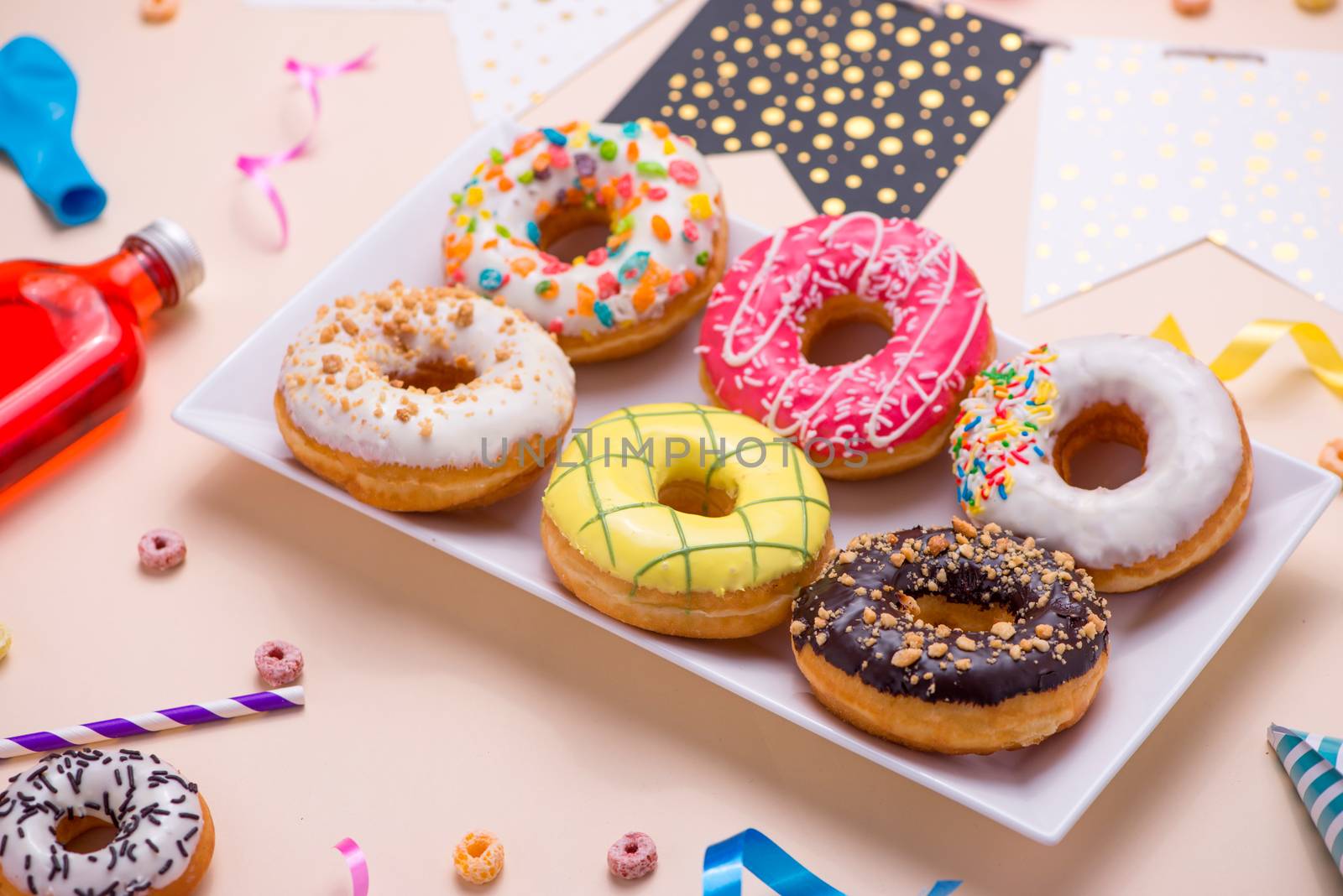 Party. Colourful round glazed donuts and bottles of drinks on pink background.