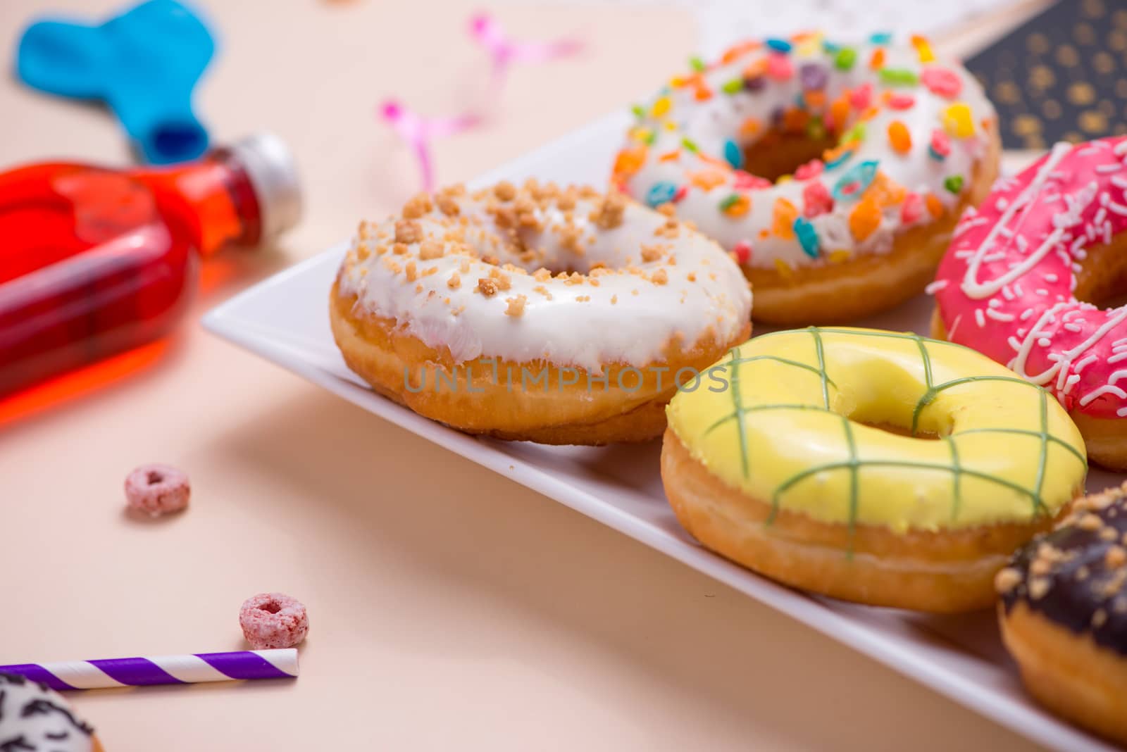 Party. Colourful round glazed donuts and bottles of drinks on pink background.