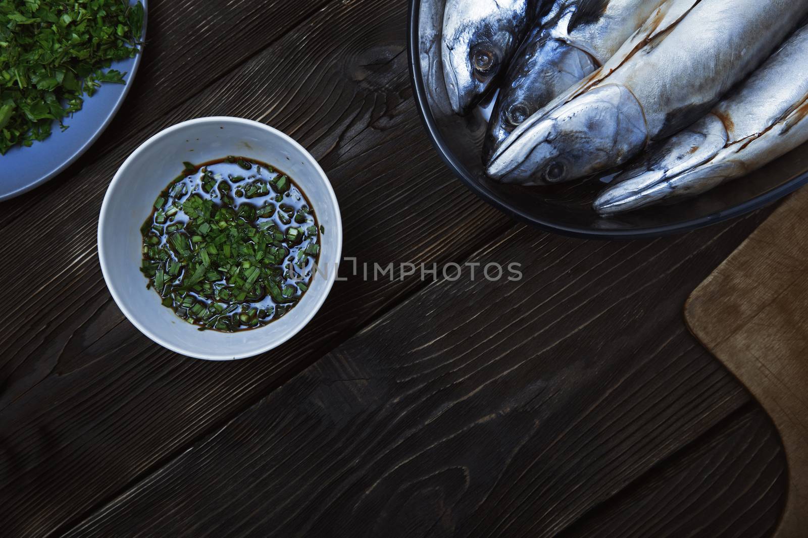 Fish with herbs and vegetables on a wooden table