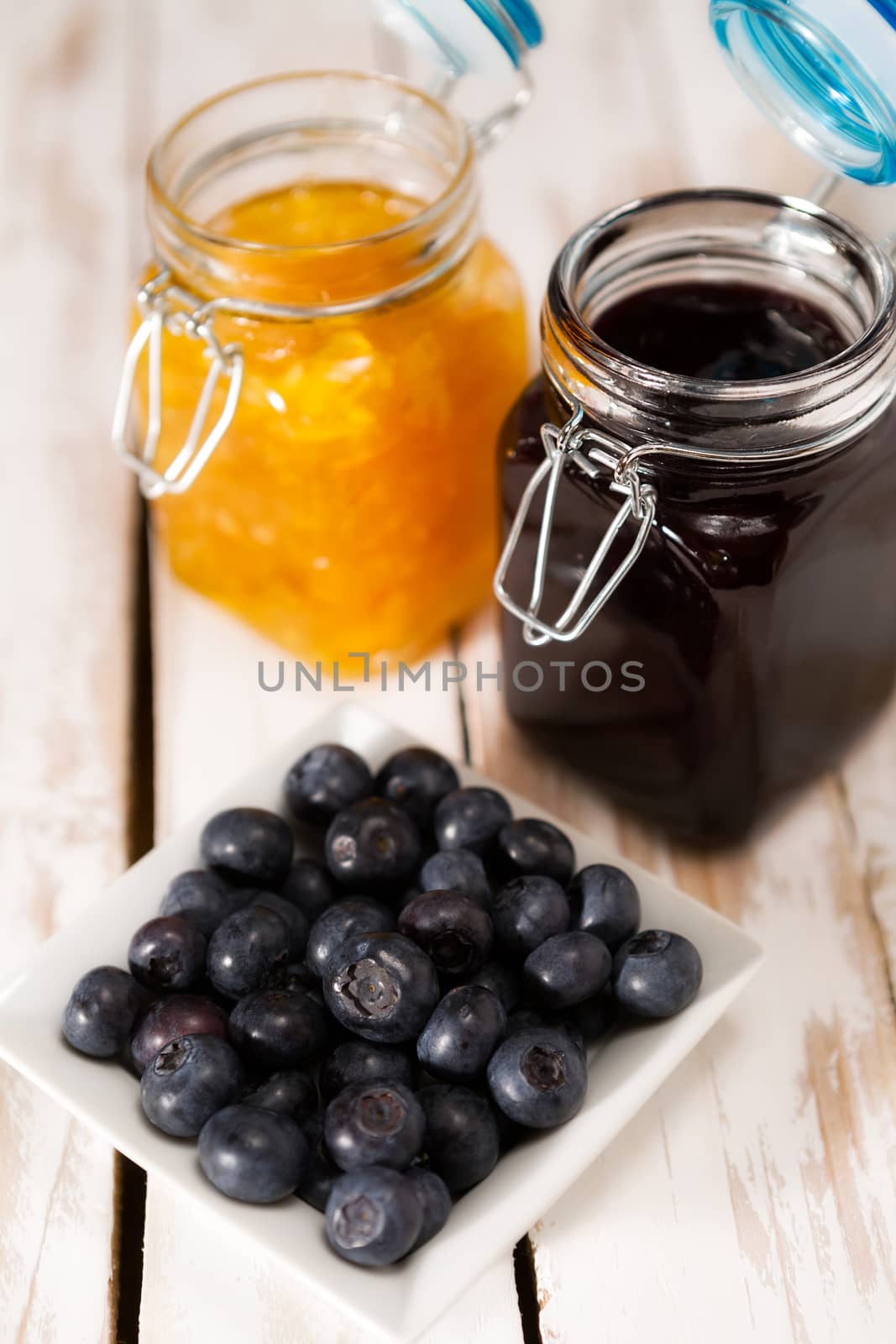 Blueberries with orange and blueberry jam over a wooden table