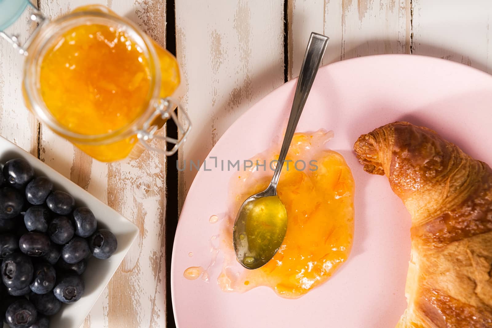 Closeup of croissant and orange jam over a wooden table by LuigiMorbidelli