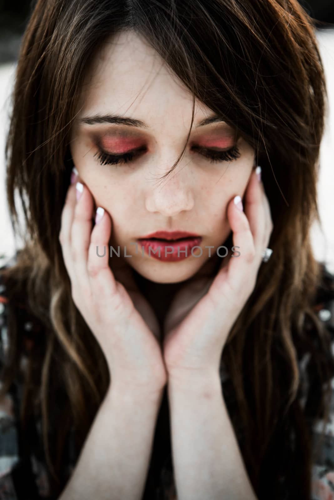 Young lady with beautiful red lipstick and dark red closed eyes.