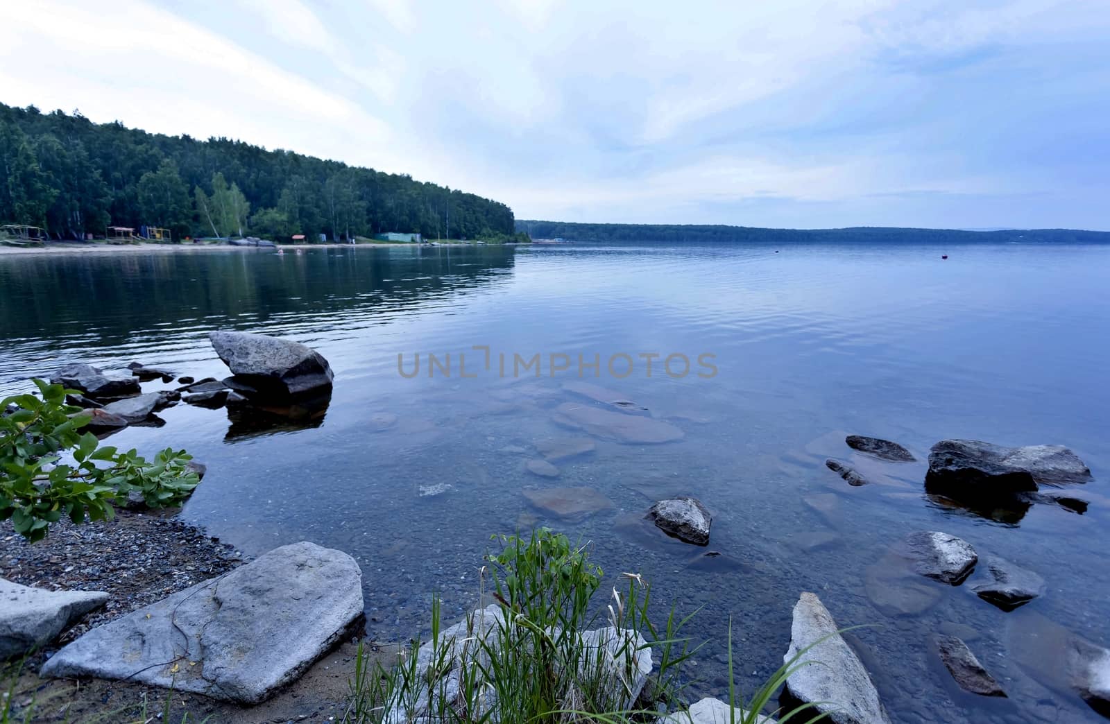 quiet lake Uvildy early in the morning, clear water, clear bottom, South Ural, in the distance are seen the Ural mountains