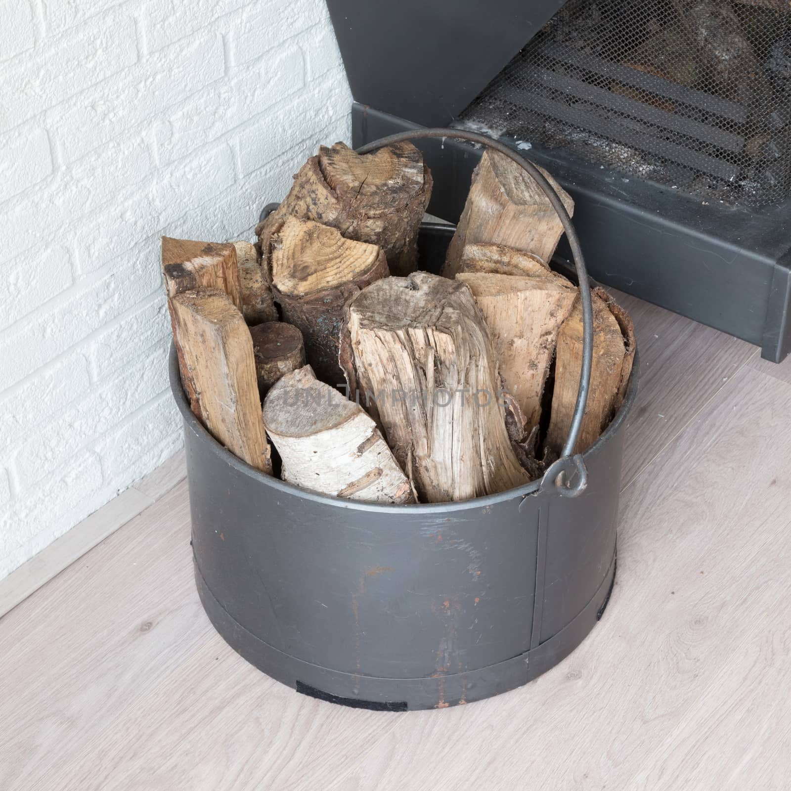 Metal basket of firewood, standing next to a fireplace