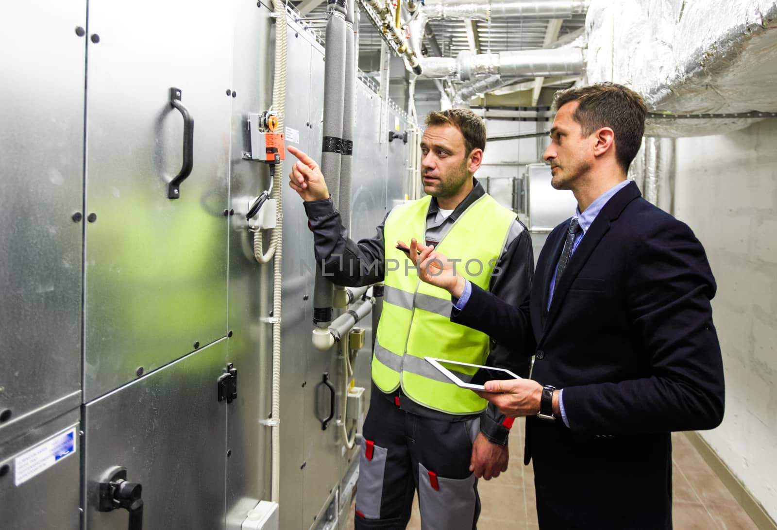 Worker and manager in electrical switchgear room of CNC plant