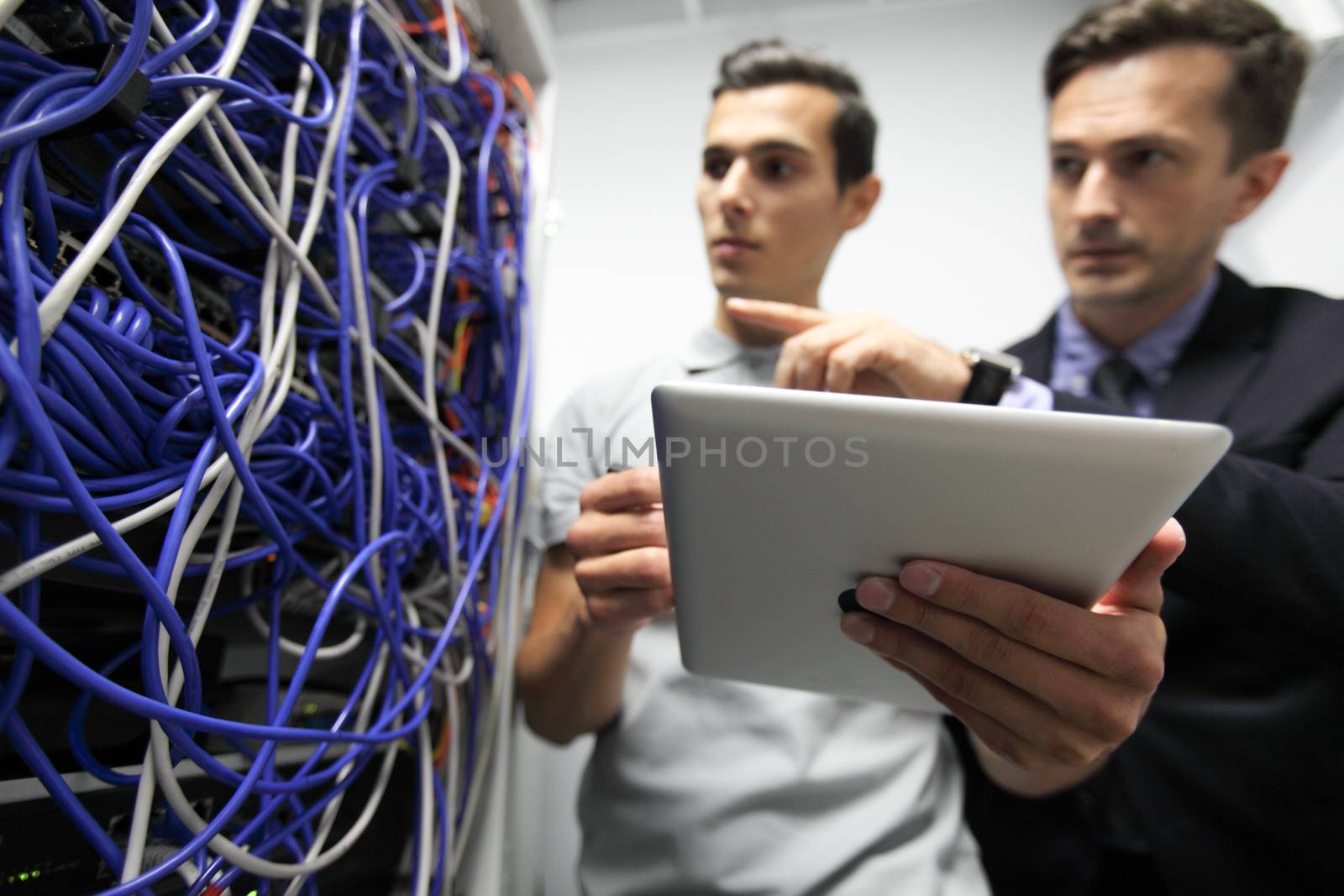 Young engeneer and manager in network server room with digital tablet