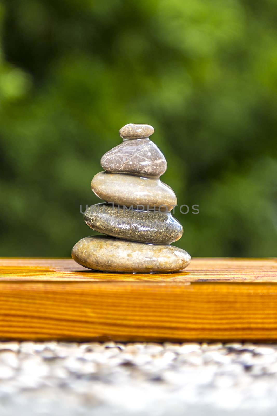 Wet zen stones on wood with green background