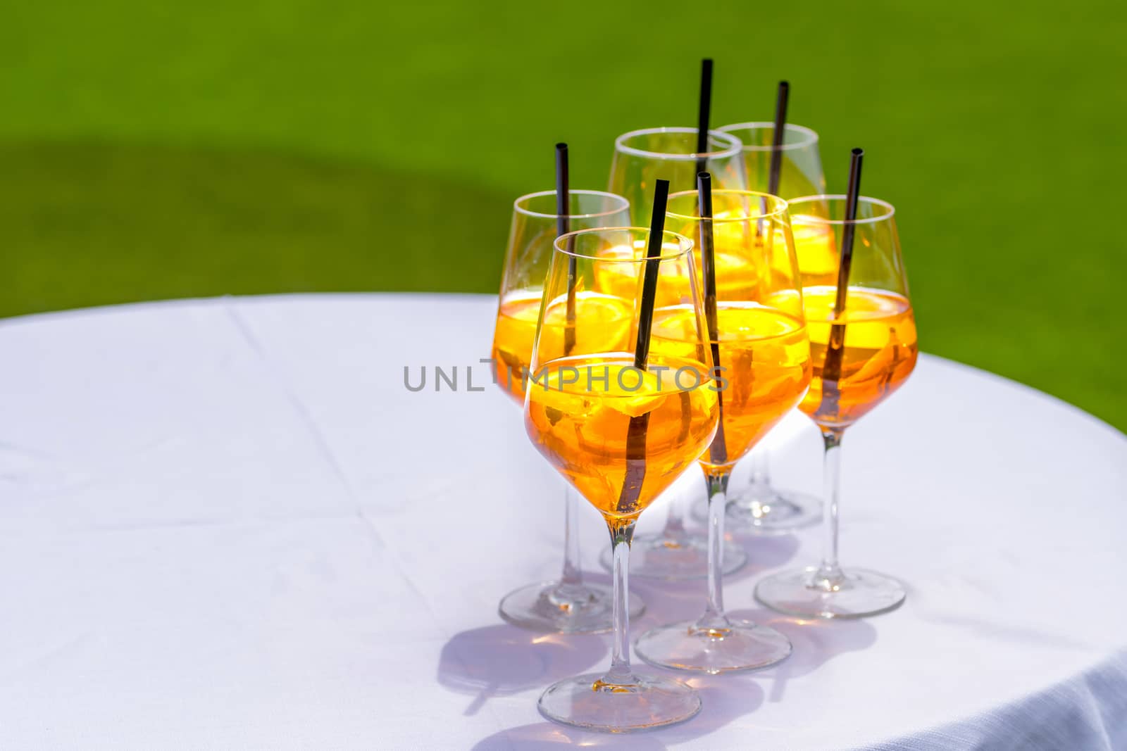 Popular Italian aperitif made with prosecco, orange bitter and soda, decorated with orange slices.Several glasses on white table with green background.